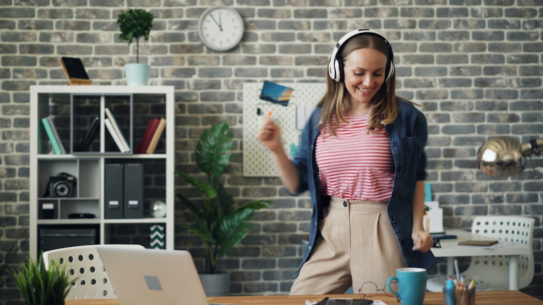 a woman wearing headphones standing in front of a laptop